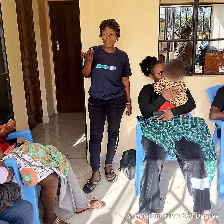 A Team Lead speaks to a group of young mothers seated with their babies